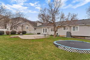 Back of house with a patio, a trampoline, and stucco siding