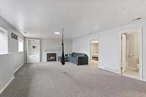 Unfurnished living room featuring a fireplace with flush hearth and light carpet