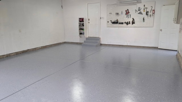 Garage featuring a gray epoxy floor finish, white walls, and built-in steps