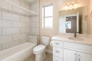 Full bath featuring vanity, washtub / shower combination, healthy amount of natural light, and a ceiling fan