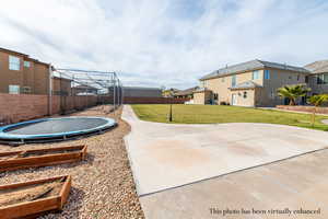 Fenced backyard featuring a trampoline