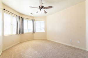 Empty room featuring a ceiling fan, light carpet, and a textured ceiling