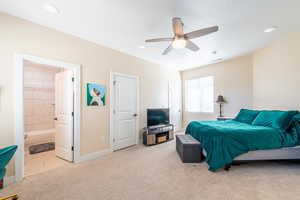 Bedroom with light carpet, a ceiling fan, ensuite bathroom, and recessed lighting