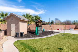 View of jungle gym featuring a fenced backyard and a storage shed