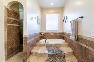 Full bath with a bath, tile walls, a wainscoted wall, and a walk in shower