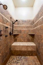 Full bathroom featuring a textured ceiling and a tile shower