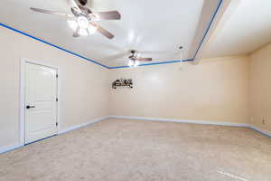 Carpeted empty room with a ceiling fan and baseboards