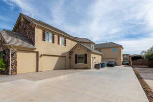 Traditional home with stucco siding, driveway, stone siding, and a gate