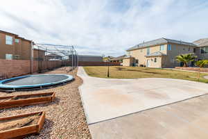 Fenced backyard featuring a trampoline and a residential view