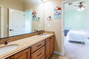 Bathroom with double vanity, a ceiling fan, ensuite bath, and light colored carpet