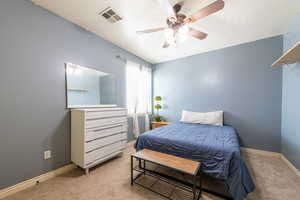 Bedroom with light carpet, a ceiling fan, and a textured ceiling