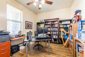 Office with light wood finished floors and a ceiling fan