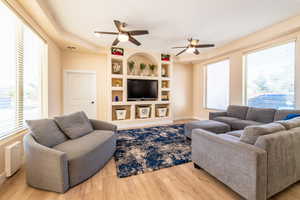 Living room with built in shelves, plenty of natural light, and light wood-type flooring