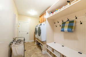 Laundry room featuring washing machine and dryer, cabinet space, and light tile patterned floors