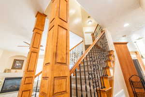 Stairway featuring a tiled fireplace, a textured ceiling, recessed lighting, and ceiling fan