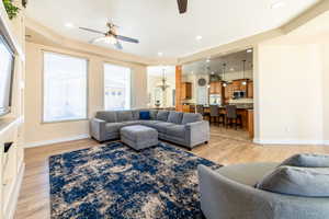 Living area with suspended lighting, ceiling fan, and light wood-style floors