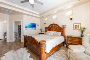 Bedroom with a tray ceiling, wood finished floors, and a ceiling fan