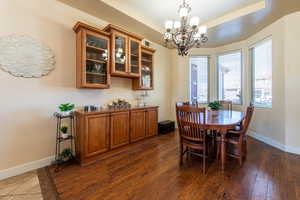 Dining area featuring suspended lighting, a raised ceiling, and dark wood-type flooring