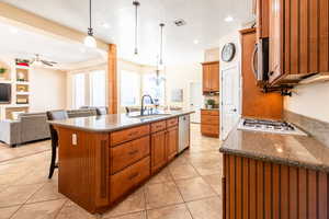 Kitchen with open floor plan, a kitchen bar, dark stone counters, wood finish cabinets, and a textured ceiling
