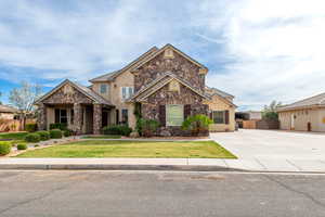 View of front facade featuring stone siding, stucco siding, and concrete driveway