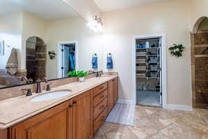 Full bathroom featuring walk in shower, a walk in closet, double vanity, and light tile patterned floors