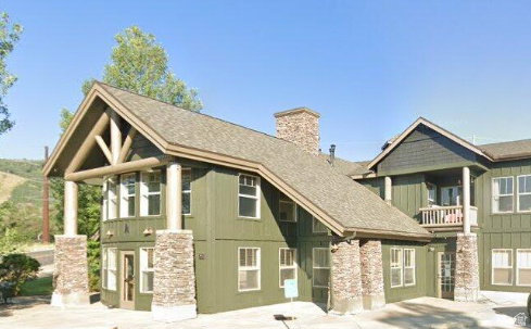 View of front of home with a balcony, a chimney, and board and batten siding