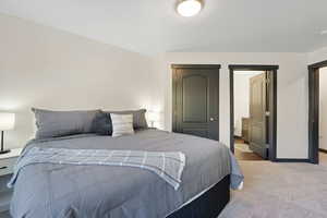 Bedroom featuring a closet, light carpet, and ensuite bath