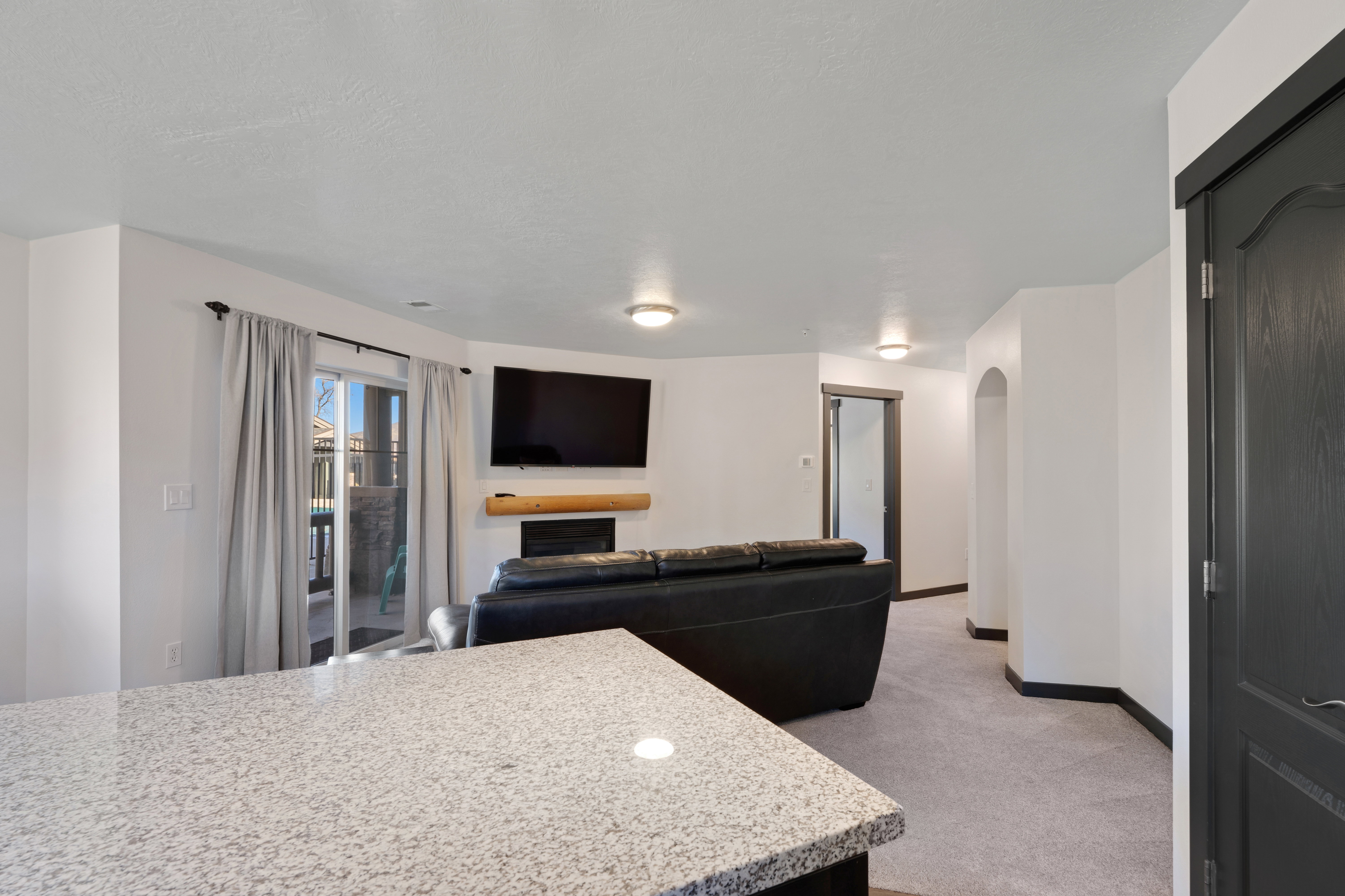 Kitchen featuring arched walkways, light carpet, a fireplace, light stone countertops, and open floor plan