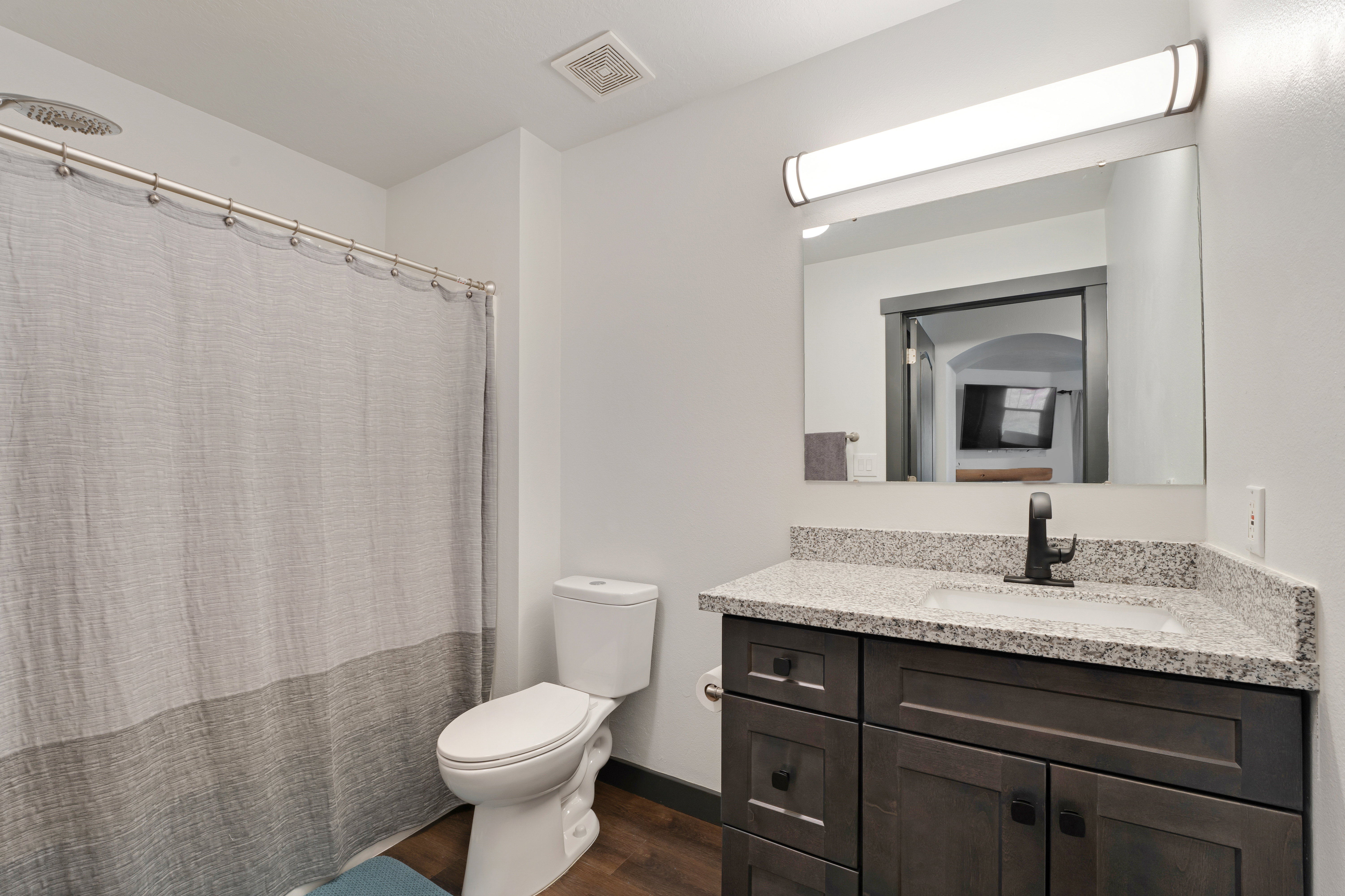 Full bathroom with vanity, curtained shower, and dark wood-style floors