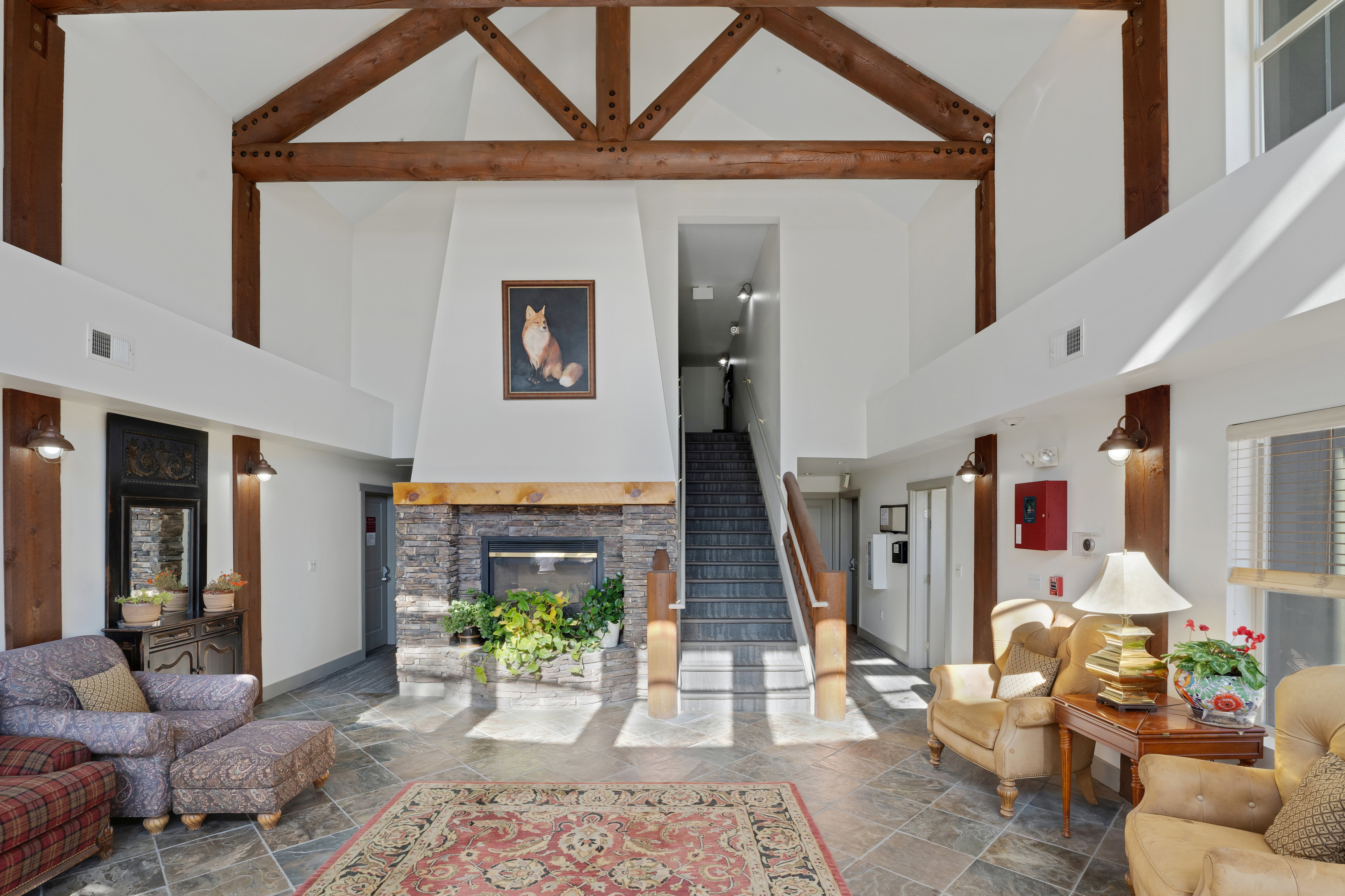 Living area featuring stone tile floors, a stone fireplace, and lofted ceiling