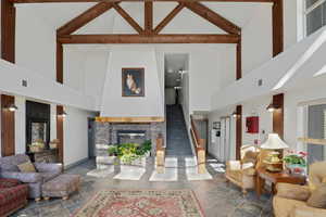 Living area featuring stone tile floors, a stone fireplace, and lofted ceiling