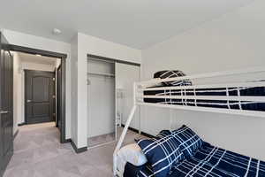 Bedroom with light colored carpet and a closet