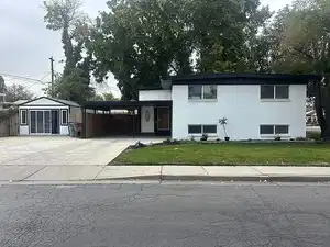 Split level home featuring an attached carport, an outdoor structure, concrete driveway, and brick siding