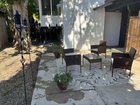 Outdoor patio area with concrete surfacing, white exterior wall, and a wooden fence