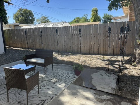 Outdoor patio featuring a concrete surface, gravel landscaping, and a wood privacy fence