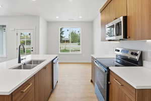 Kitchen featuring stainless steel appliances, wood finish cabinetry, modern cabinets, recessed lighting, and an island with sink