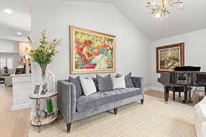 Living room featuring light wood-type flooring, suspended lighting, and lofted ceiling