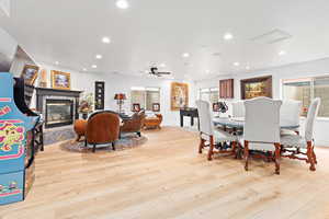 Dining room featuring light wood-style flooring, a glass covered fireplace, recessed lighting, and a ceiling fan