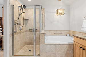 Full bathroom with vanity, a garden tub, a shower stall, and a chandelier