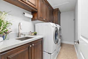 Laundry area with cabinet space, washing machine and dryer, and light tile patterned flooring