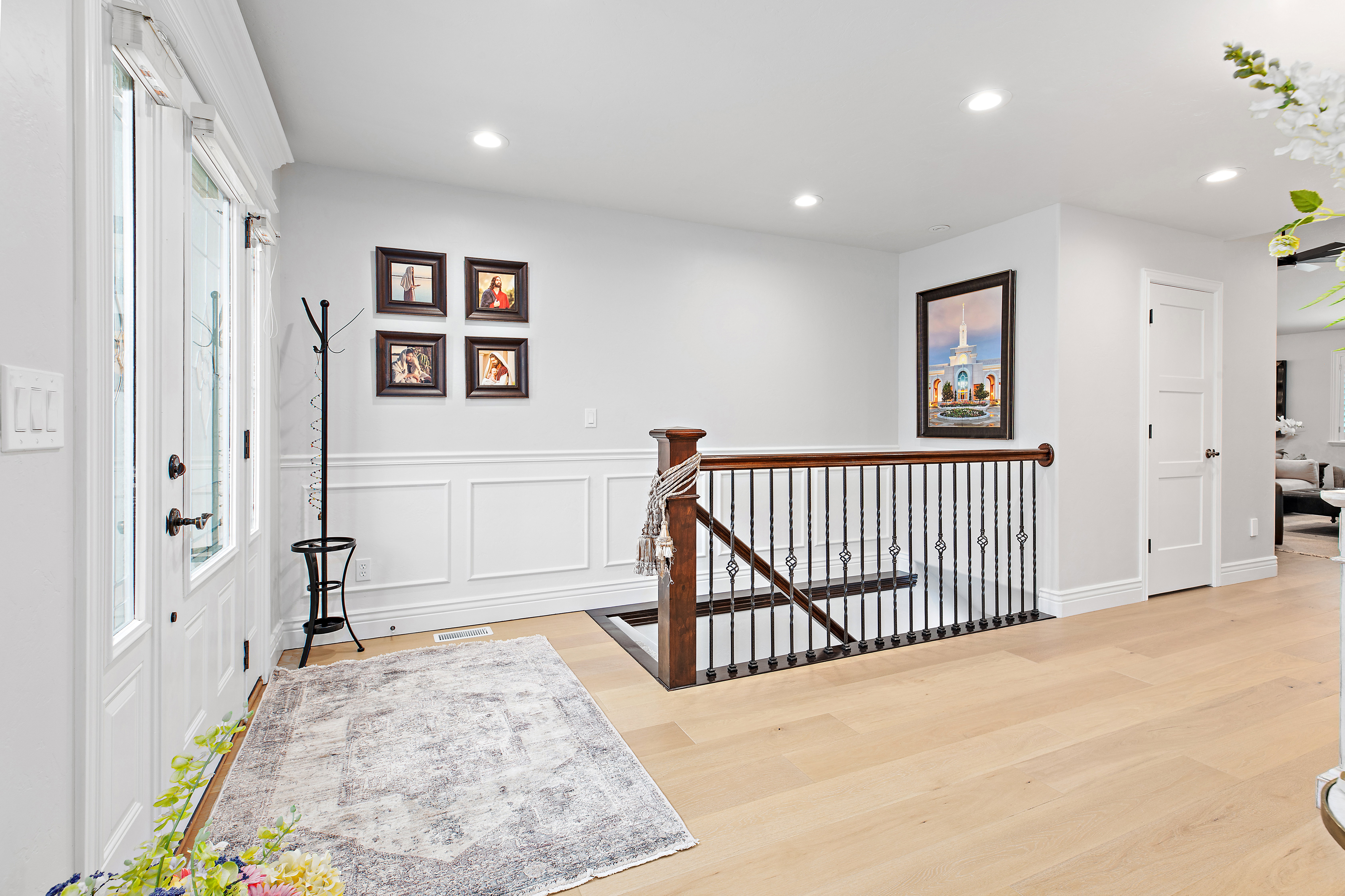 Corridor featuring an upstairs landing, light wood finished floors, recessed lighting, a decorative wall, and wainscoting