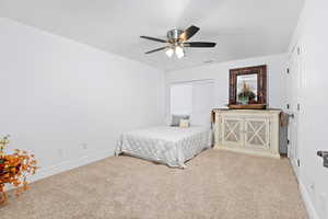 Carpeted bedroom with a ceiling fan and baseboards