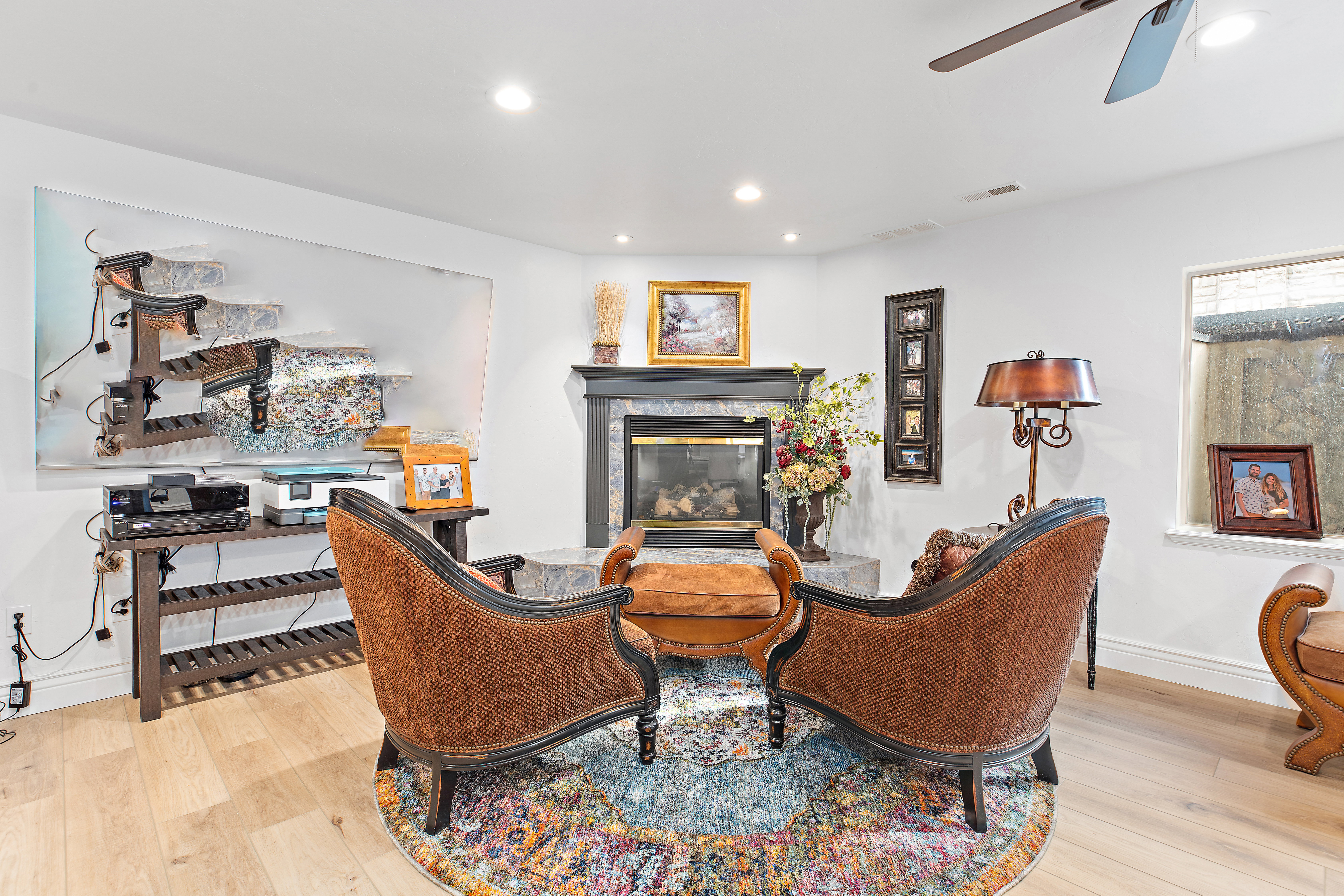 Living area featuring light wood finished floors, a glass covered fireplace, recessed lighting, and a ceiling fan