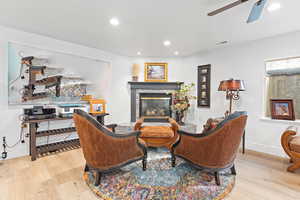 Living area featuring light wood finished floors, a glass covered fireplace, recessed lighting, and a ceiling fan