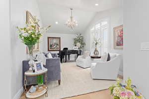 Living room featuring wood finished floors, vaulted ceiling, and suspended lighting