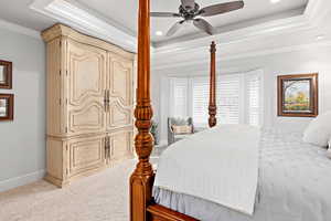 Bedroom with ornamental molding, a tray ceiling, a ceiling fan, carpet flooring, and recessed lighting