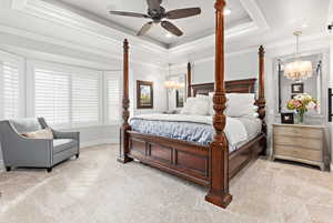 Bedroom with a ceiling fan, light carpet, crown molding, suspended lighting, and a tray ceiling