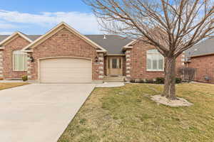 View of front of house featuring roof with shingles, an attached garage, driveway, brick siding, and a front lawn