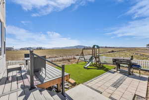 View of patio / terrace featuring a playground, area for grilling, a view of rural / pastoral area, and a deck with mountain view