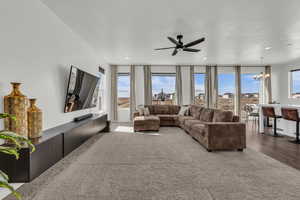 Living area featuring a ceiling fan, plenty of natural light, hanging lights, floor to ceiling windows, and wood finished floors
